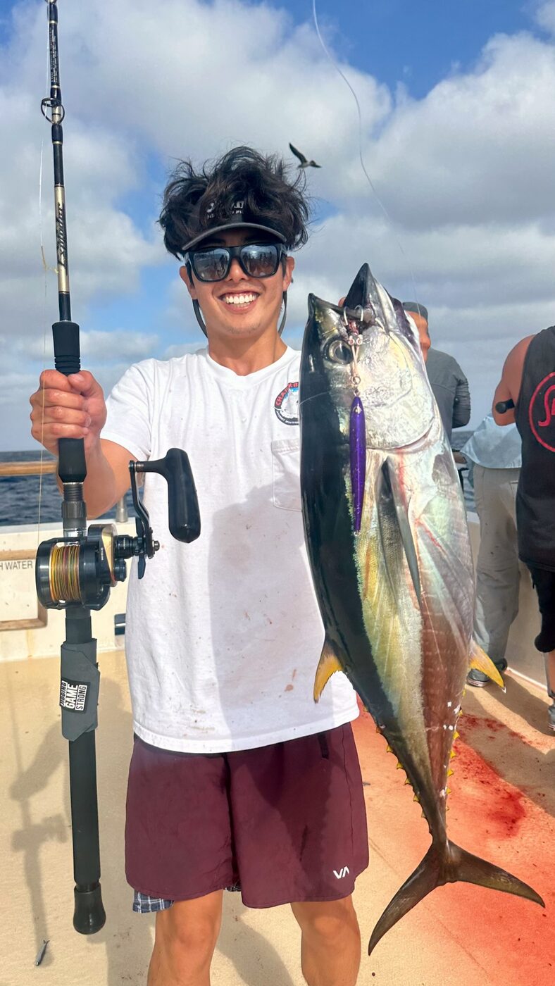 Richard holding a yellowfin tuna caught on a purple jig, conventional jigging rod in hand