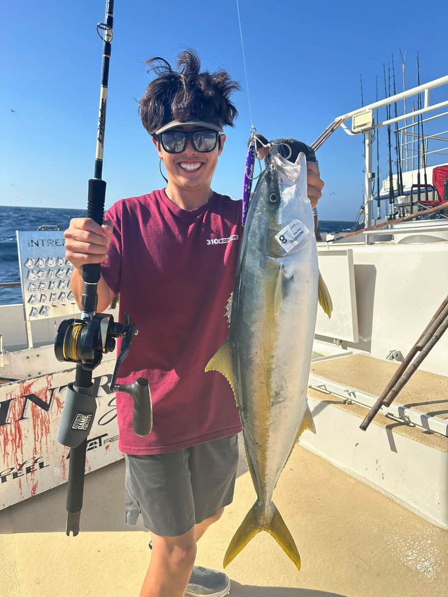 Richard holding a yellowtail caught on a purple jig, jigging rod and reel in hand