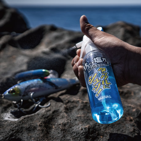 Angler spraying Varivas Salt Neutralizing Spray on a saltwater lure on the rocks