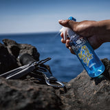 Angler spraying Varivas Salt Neutralizing Spray on pliers and tools by the ocean